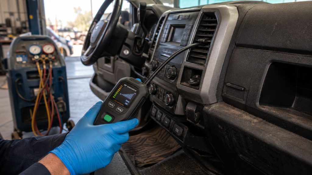 Technician checking RAM and Ford truck vents for evaporator leaks with an electronic refrigerant leak detector in Chandler