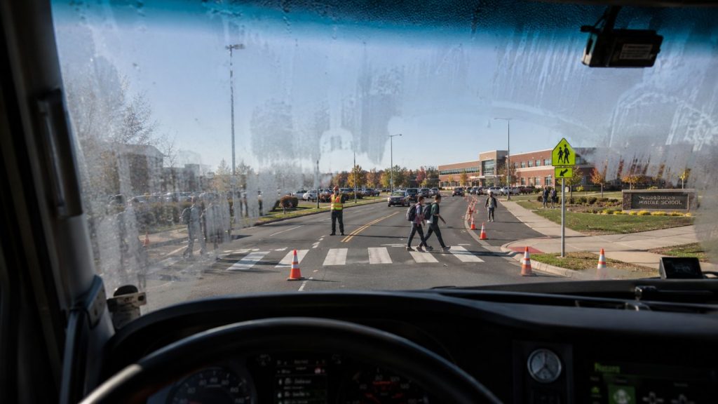 A driver's perspective from inside a truck cab showing a partially fogged windshield in a busy school zone.